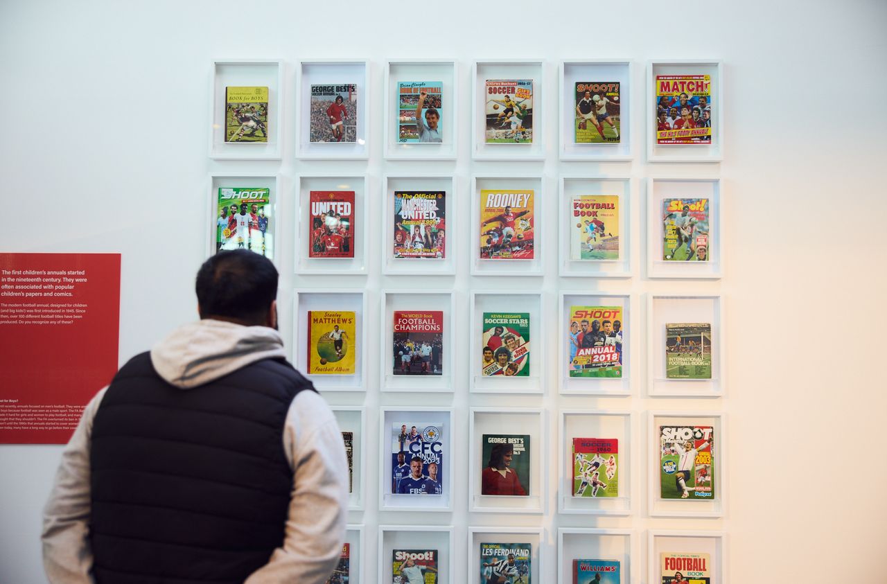 Visitor looking at a wall of framed football annuals